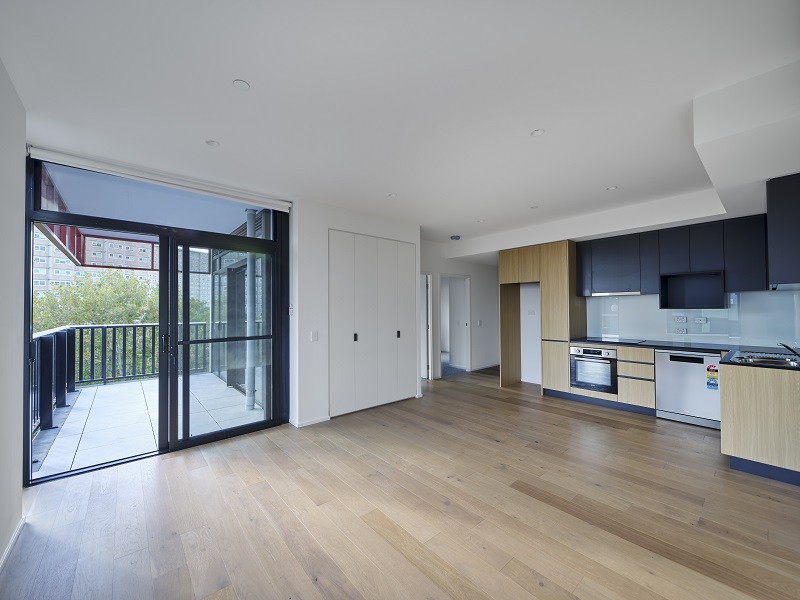 Open-plan living with kitchen along the wall and a door to the balcony