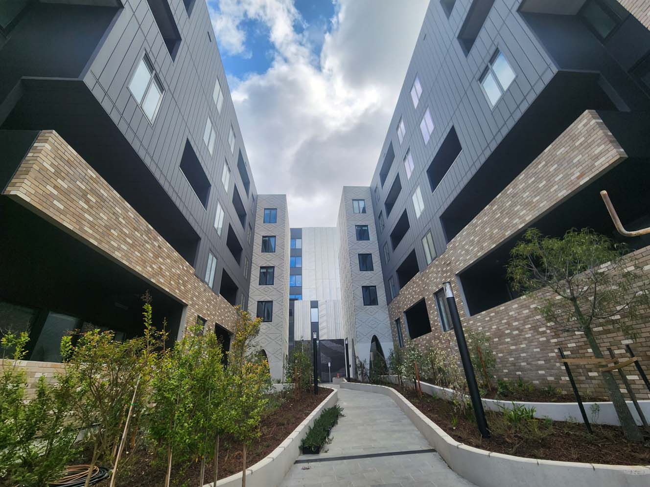 Image of North Melbourne precinct, with pedestrian pathway surrounded with greenery 